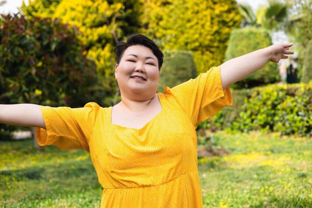 Woman in yellow enjoying outdoors with arms spread, allergy-free