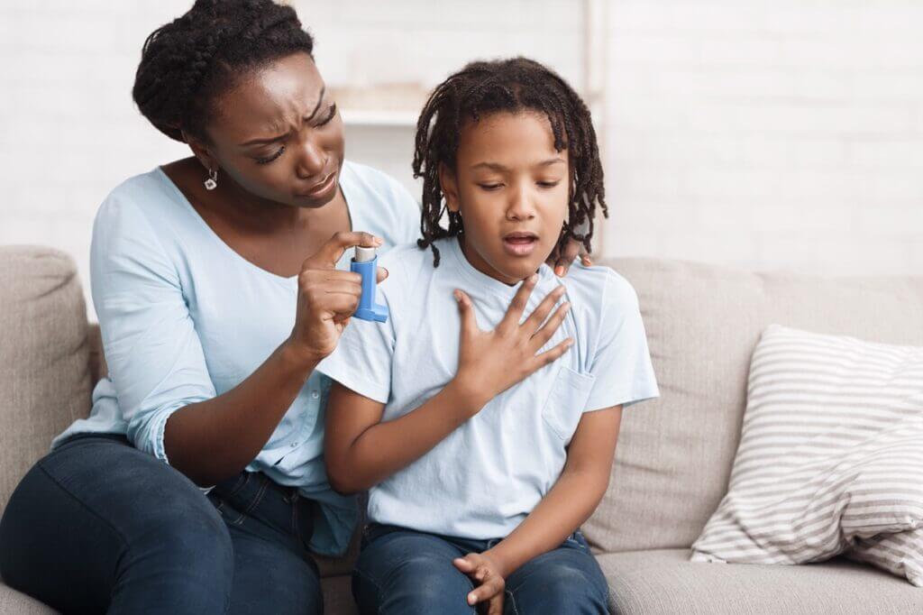 Mother helping child with asthma inhaler during allergy flare-up