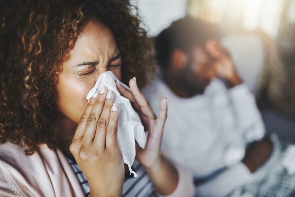 Woman sneezing indoors with winter allergy symptoms