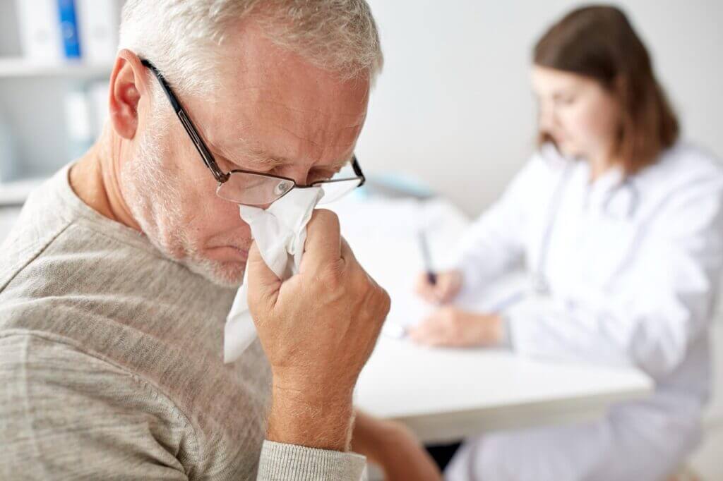Older man sneezing during allergy clinic visit